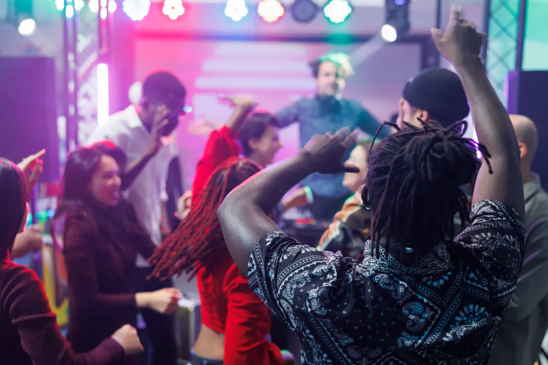 Guests dancing with raised hands under colourful stage lights
